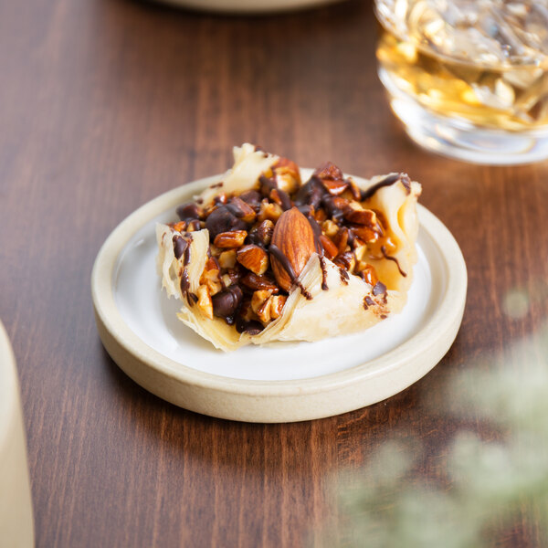 A Chef & Sommelier white stackable plate with food, nuts, and chocolate.