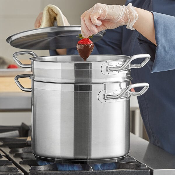 A person using a Vigor stainless steel double boiler to melt chocolate for strawberries.