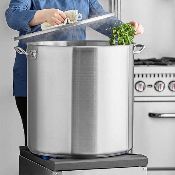 A woman standing in front of a Vigor stainless steel stock pot on a counter.