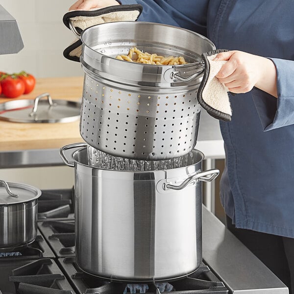 A person using a Vigor stainless steel pasta cooker.