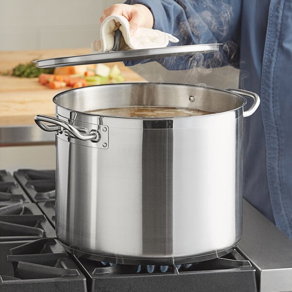 A person using a Vigor stainless steel stock pot on a stove.
