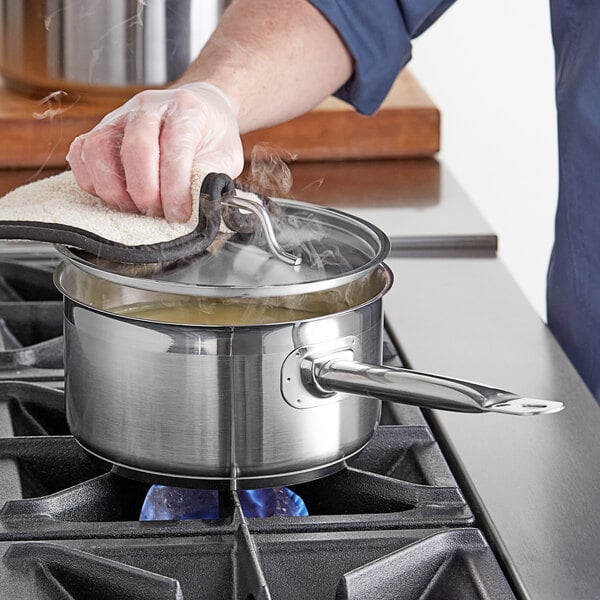 A person cooking food in a Vigor stainless steel sauce pan on a stove.