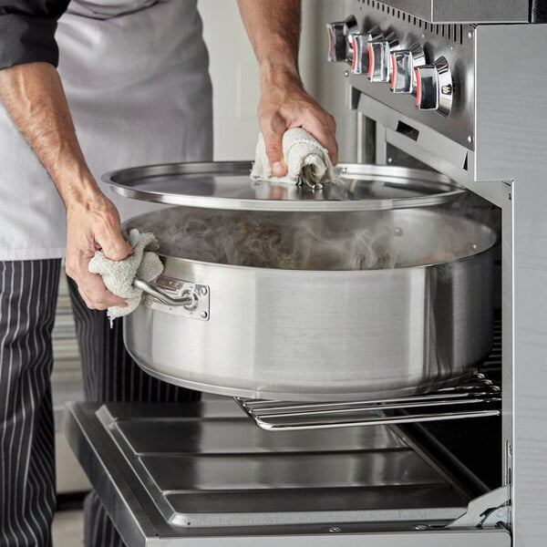 A chef using a Vigor stainless steel brazier to cook.
