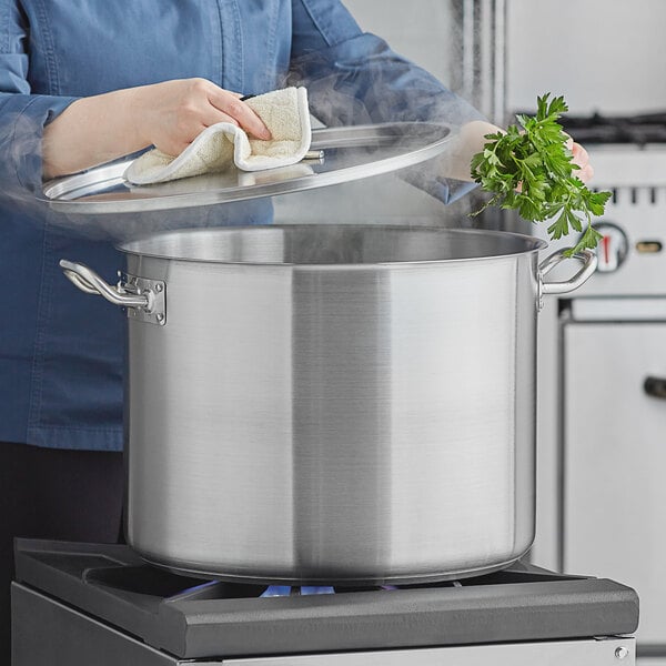 A woman using a Vigor stainless steel stock pot on a stove.