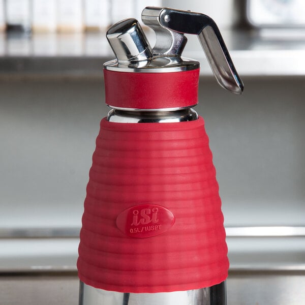 A red and silver heat protection sleeve with a handle for an iSi cream whipper.