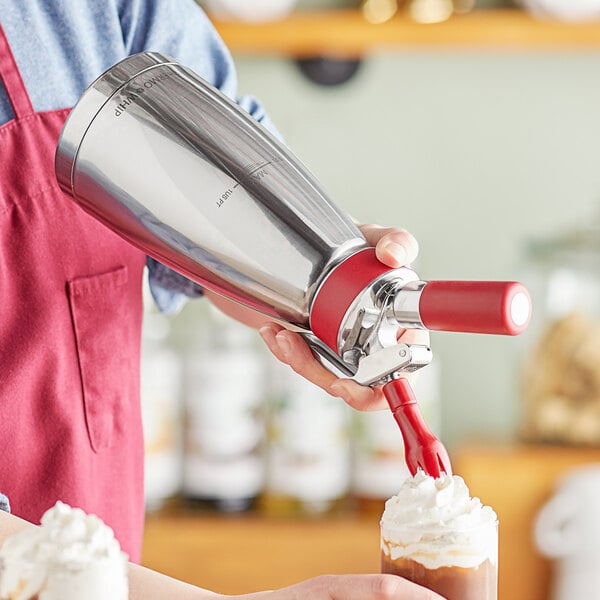 A person using the iSi Thermo Whip to add whipped cream to a drink.