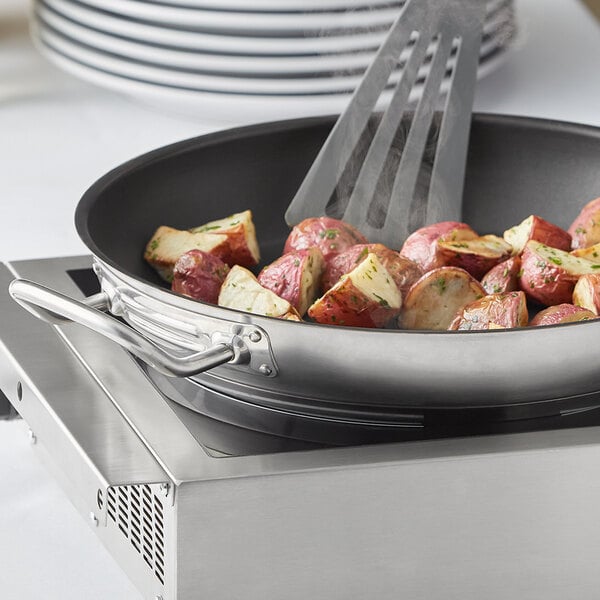 A Vigor SS1 Series stainless steel non-stick fry pan with potatoes and a spatula.
