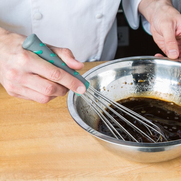 A person using a Vollrath stainless steel French whisk to mix food in a bowl.