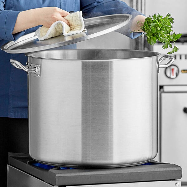 A woman using a Vigor SS1 Series stainless steel stock pot on a stove.