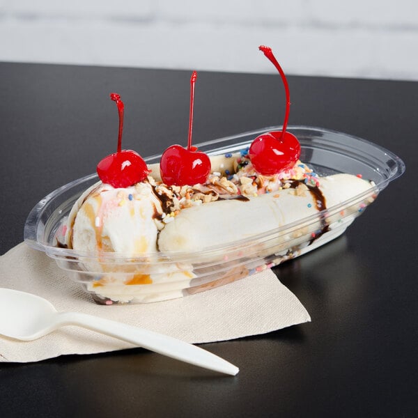 A Carnival King clear plastic banana split boat with a banana split, cherries, and chocolate toppings.