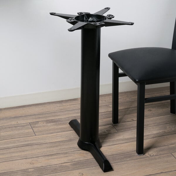 A black Lancaster Table & Seating end table base on a table with a black chair