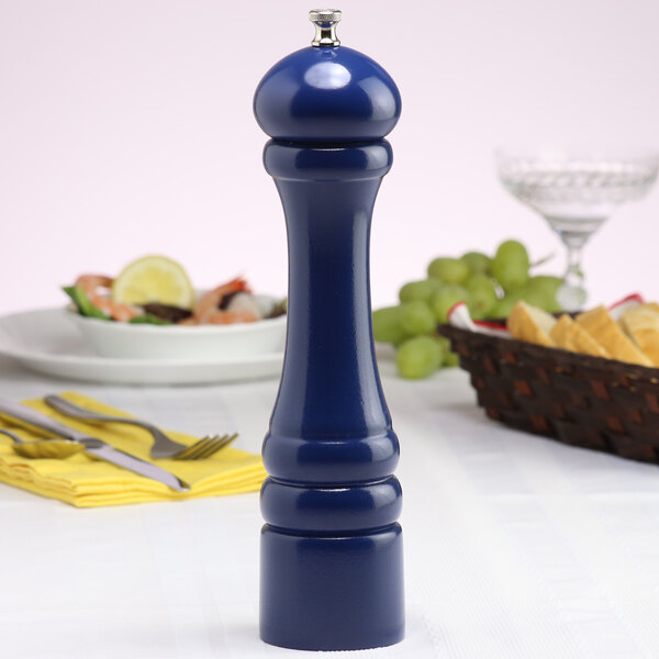 A Chef Specialties cobalt blue pepper mill on a table with food.
