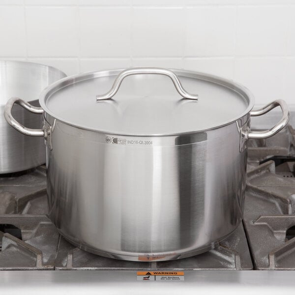 A Vollrath Lincoln stainless steel sauce pot with a lid on a stove.
