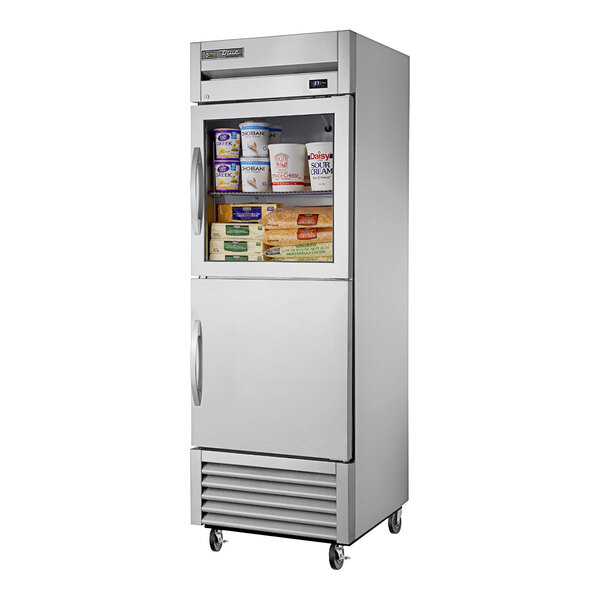 A True stainless steel reach-in refrigerator with a glass top and solid bottom half door open to reveal food inside.