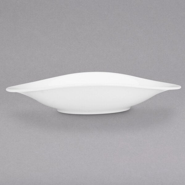 A white Villeroy & Boch porcelain oval plate with a curved edge on a grey background.