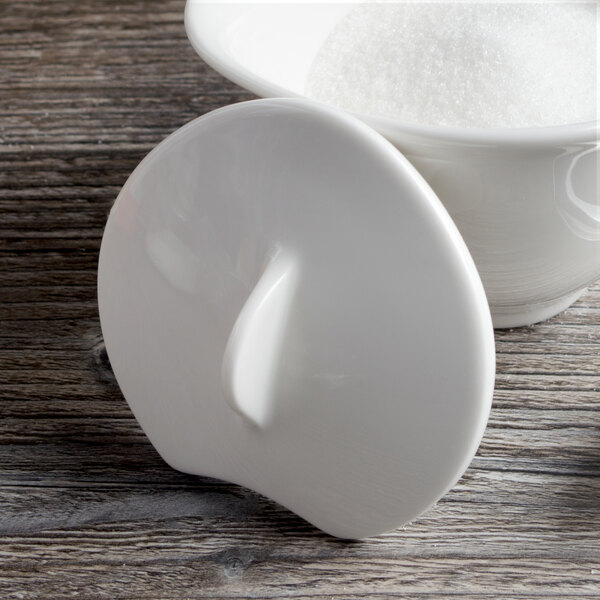 A white Villeroy & Boch porcelain sugar bowl lid on a white bowl filled with sugar.