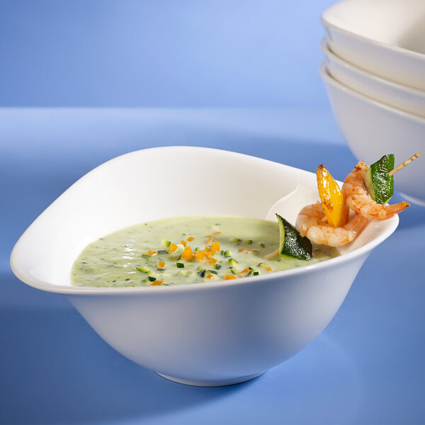 A stack of white Villeroy & Boch Dune deep coupe bowls filled with soup with shrimp and vegetables.