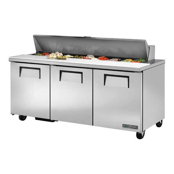 A True refrigerated sandwich prep table with three doors on a counter.
