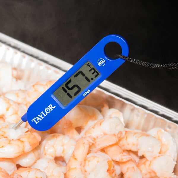 A blue Taylor digital probe thermometer on a tray of shrimp.