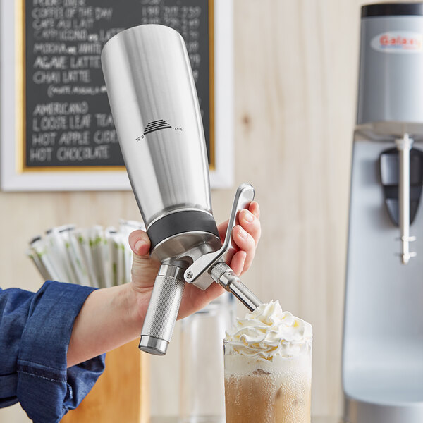 A hand holding a silver Chef Master whipped cream dispenser.