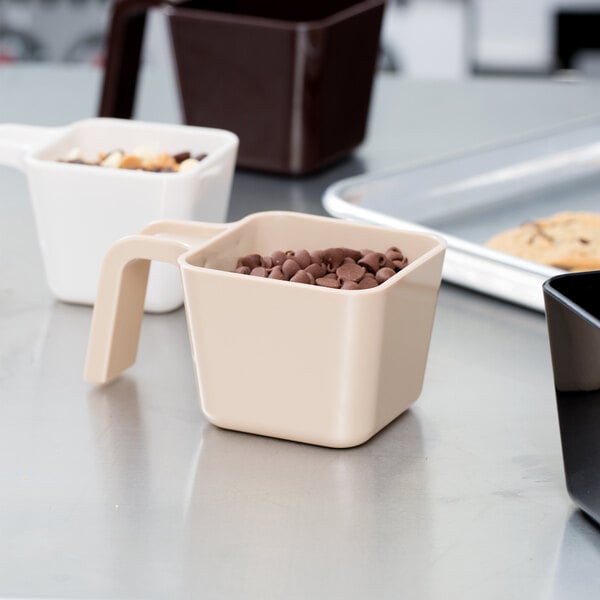 A Carlisle beige polycarbonate portion scoop filled with chocolate chips.