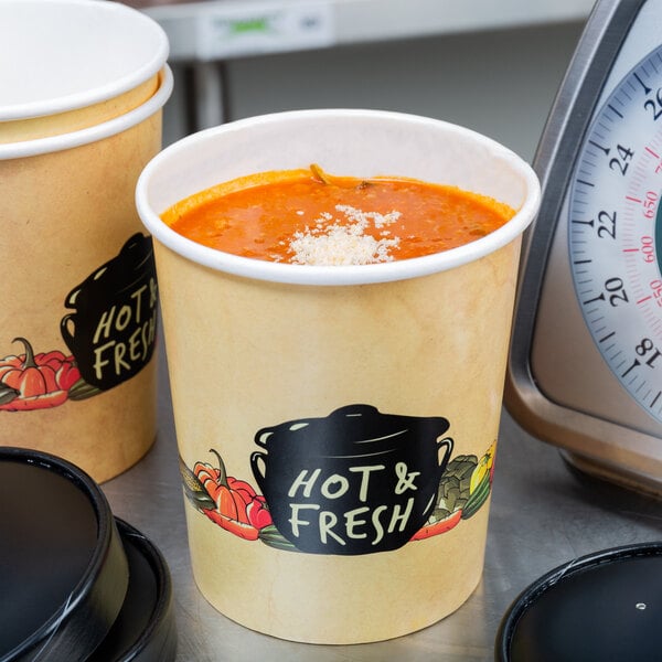 Two Choice paper soup cups filled with soup on a black surface next to a scale.