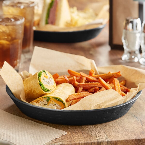 A plate of food with a sandwich and a side of fries in a Choice black plastic diner food basket.