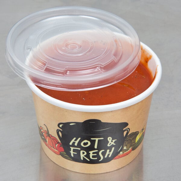 A Choice paper soup container filled with soup and covered with a plastic lid.