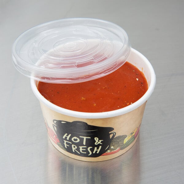 A Choice paper soup container with a plastic lid on top full of soup.