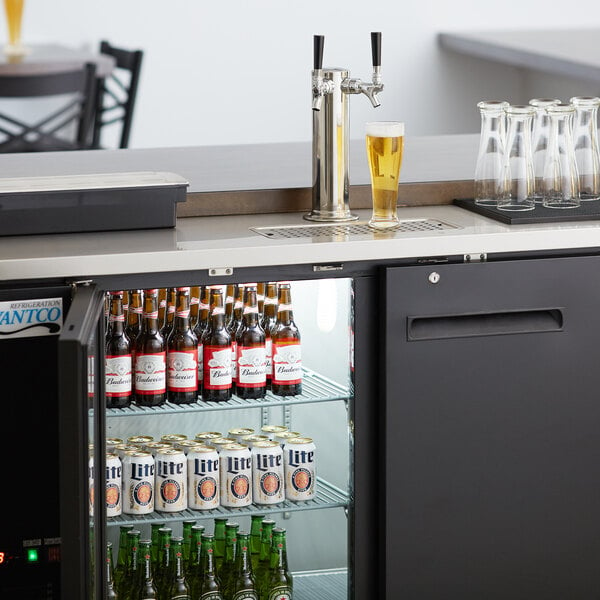 A black Avantco kegerator with a 2-tap tower on a refrigerator full of beer.