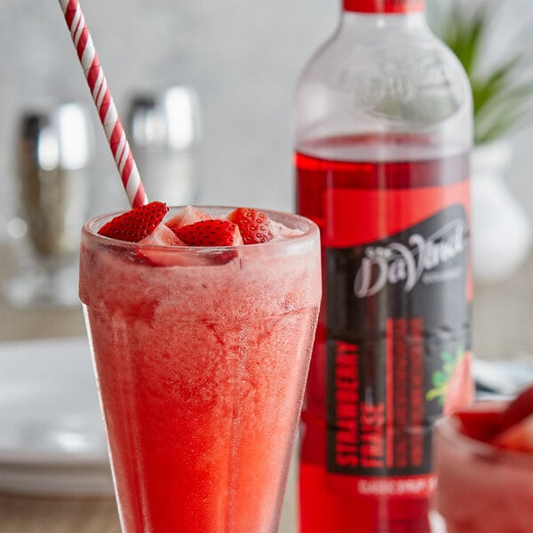 A glass of strawberry juice with a straw in a DaVinci Gourmet Classic Strawberry Fruit Syrup drink.