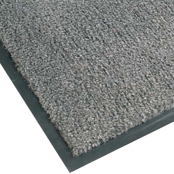 A close-up of a grey Notrax carpet entrance mat with black trim.