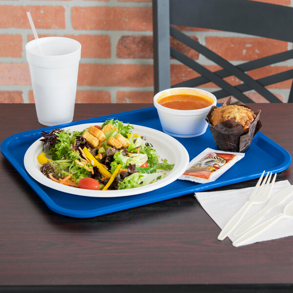 A Vollrath royal blue plastic fast food tray with a salad, muffin, and bowl of soup on it.
