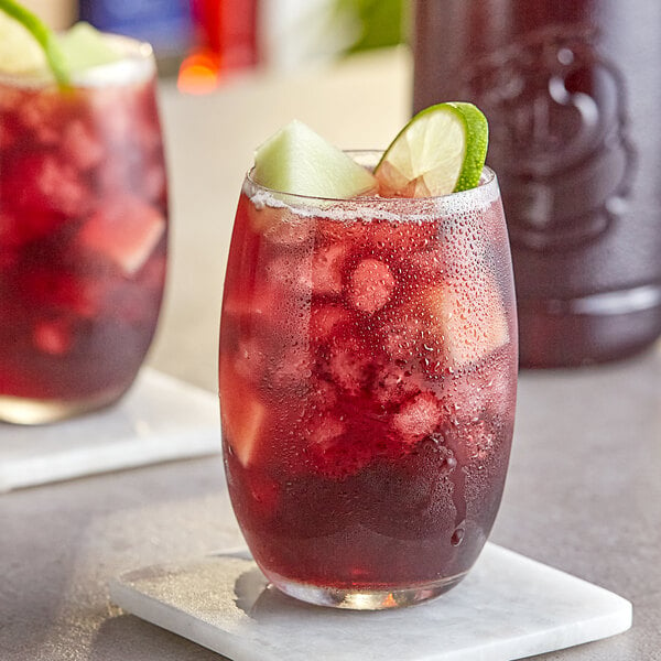 A glass of Finest Call red sangria with a lime slice on the rim.