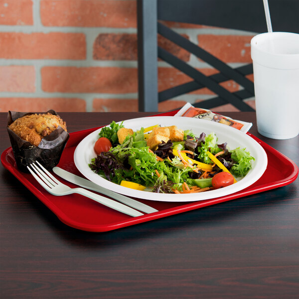 A red Vollrath fast food tray with a salad and muffin on it.