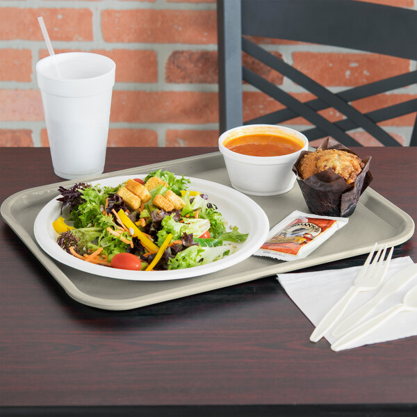 A Vollrath almond plastic fast food tray with a salad, muffin, and cup of soup on it.