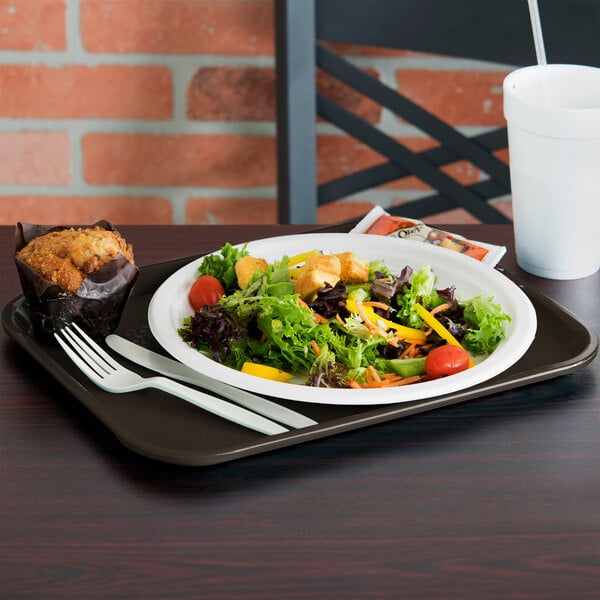 A brown plastic fast food tray with a salad, muffin, and white cup on it.