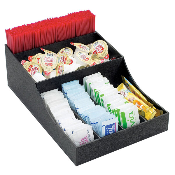 A black Cal-Mil coffee condiment organizer on a counter with a variety of different condiments inside.