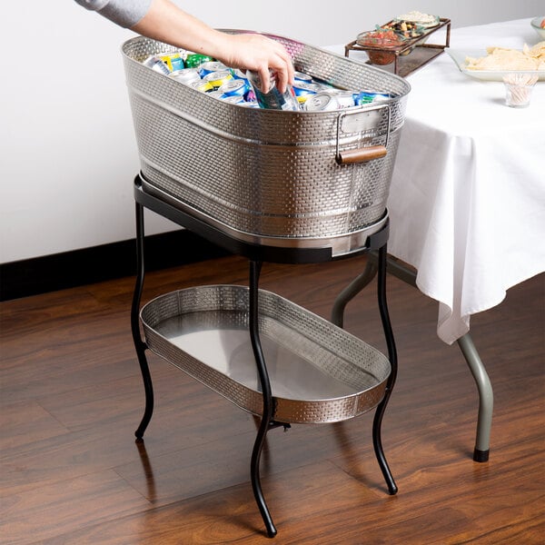 A person putting beverages in a stainless steel beverage tub on a table.
