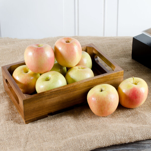 A Tablecraft acacia wood crate filled with apples on a table.