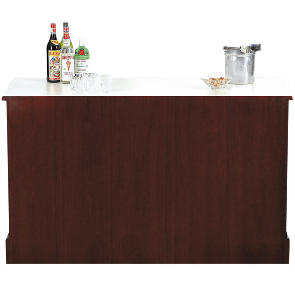 A Bon Chef portable wood back bar with bottles and glasses on top.