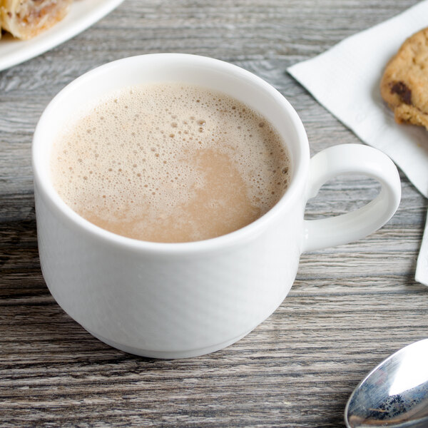 A white Villeroy & Boch porcelain cup of coffee with cookies on a wooden table.