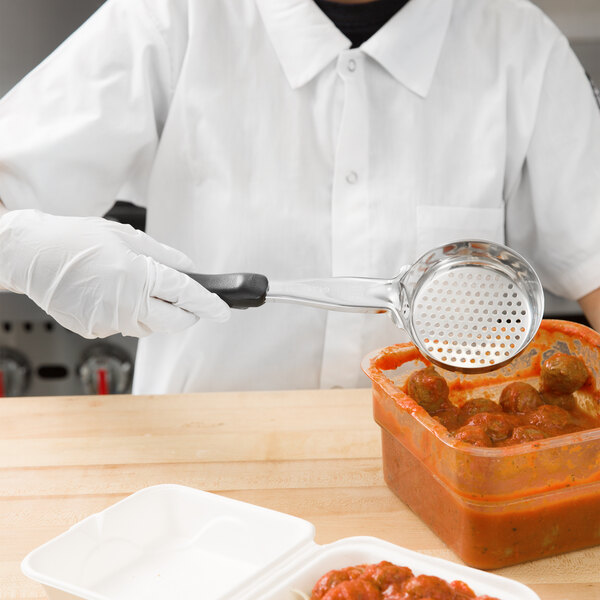 A person using a Vollrath black perforated round Spoodle to serve red sauce.