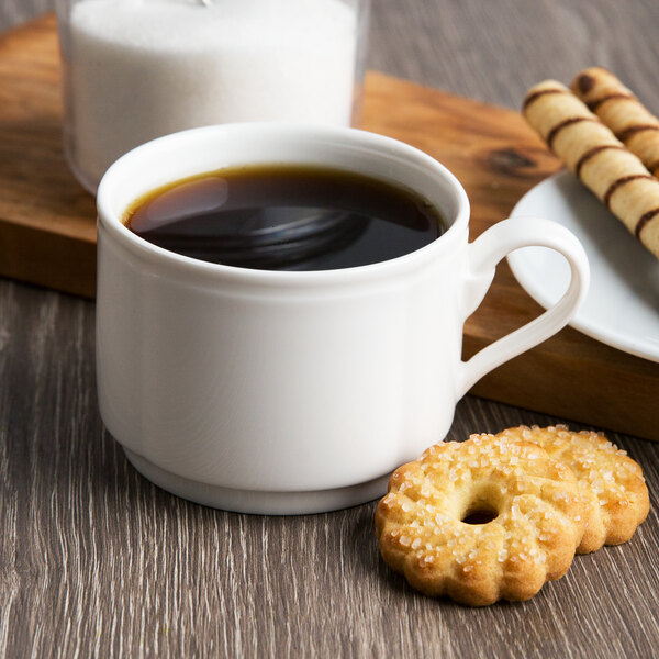 A Villeroy & Boch white porcelain stackable cup filled with coffee next to a cookie.