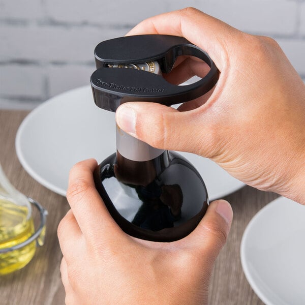 A person using a Franmara Dual Blade Wheel Wine Foil Cutter to open a bottle of wine on a kitchen counter.