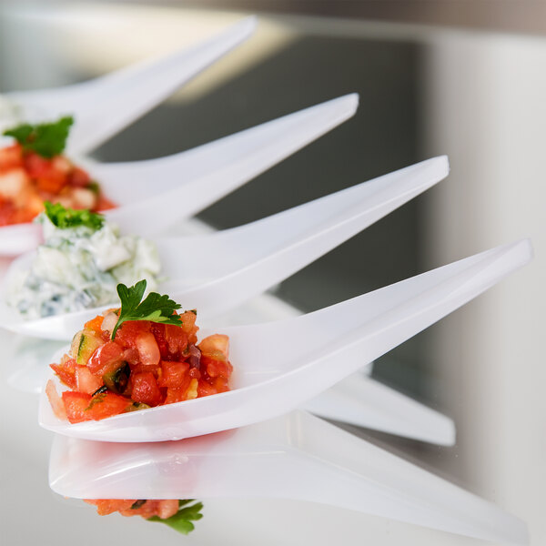 A group of Fineline white plastic spoons with food on them.