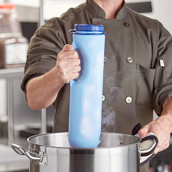 A man in a chef's uniform using a blue Vollrath Safety Mate Insta Chill cooling paddle.