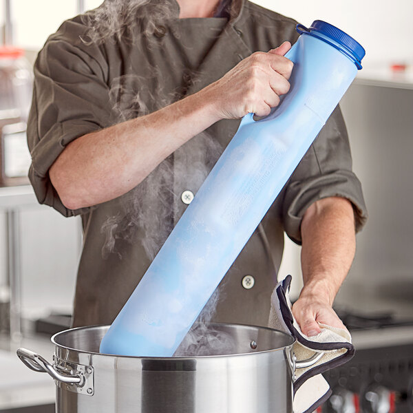 A man in a chef's uniform using a Vollrath Insta Chill Cooling Paddle to chill a blue container.
