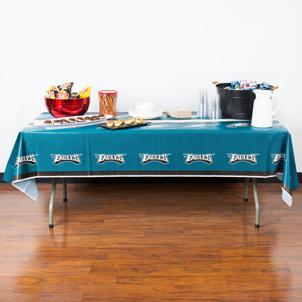 A Philadelphia Eagles table cover on a table with food.