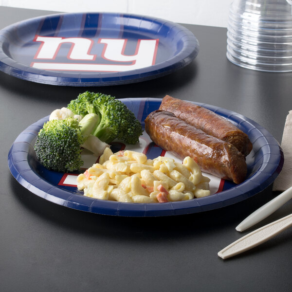 A New York Giants paper dinner plate with pasta and sausage on it.